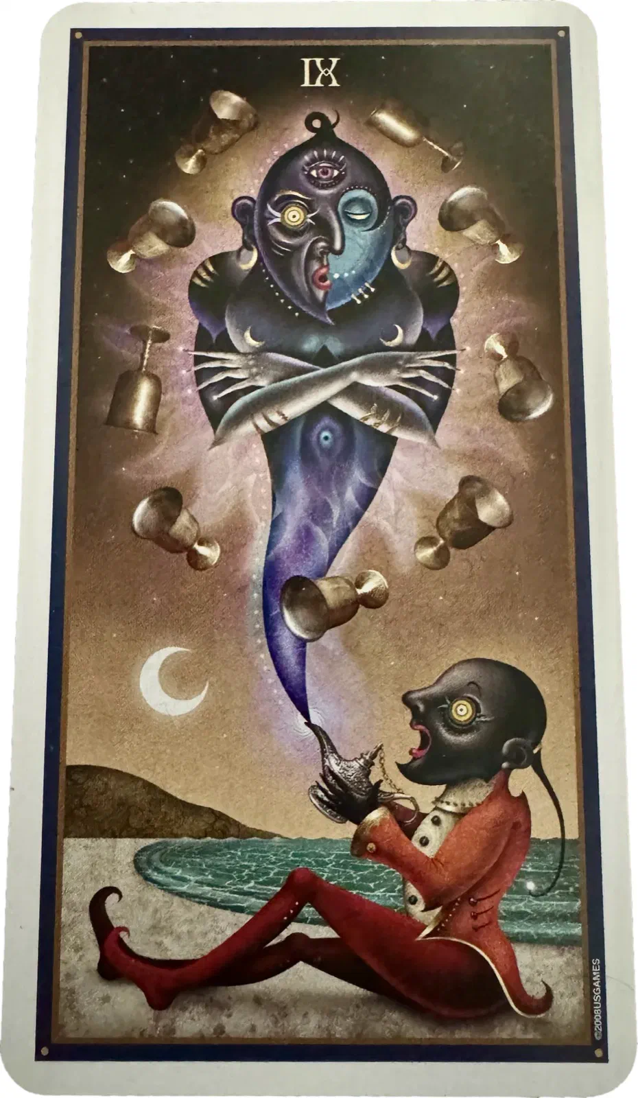 The Nine of Cups. Down on the sand by the water, a small figure in a red suit and pointed shoes holds up a lamp. Rising out of it and filling the top two-thirds of the card is an enormous blue djinn, arms folded, three eyes in its face with one of them shut, nine gold cups drifting in the air around it.