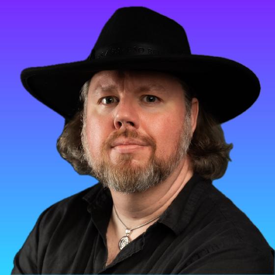 Matt Stine — black wide-brimmed hat, black shirt, pentacle pendant, on a violet-to-blue gradient